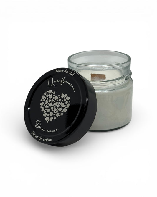 Bougie artisanale parfum au choix, ici Fleur de coton, pot en verre avec cire d'olive et mèche en bois, couvercle noir gravé "Une flamme, deux cœurs" + motif cœurs.